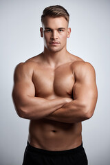 Fototapeta premium Portrait, man and bodybuilder with arms crossed on studio background, backdrop and topless abs. Sexy, serious and strong male model, sports athlete and fitness for exercise, confidence and muscles