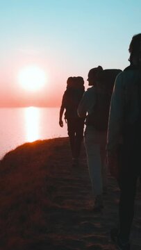 The four travelers walking on the mountain top against the sunset. slow motion