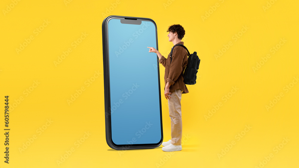 Poster guy with backpack using giant phone with empty screen, studio