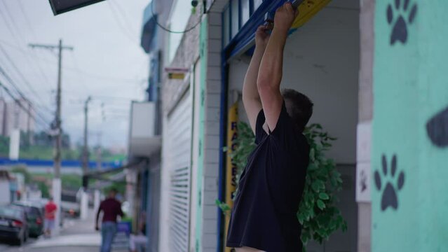 Person closing local storefront garage. Man sliding down business facade in sidewalk