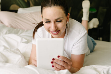 Happy woman using tablet in bedroom at home