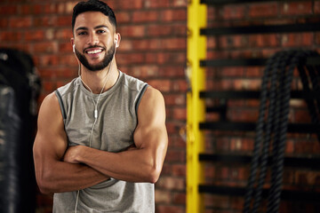 Fitness, earphones and portrait of man in gym, arms crossed and confident smile in mockup space....