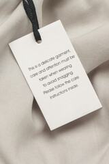 Close up of luxury clothing hang tag. Delicate garment swing tag. Laundry care washing instructions...