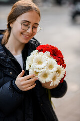 Pretty smiling woman with bouquet of fresh gerbera flowers in her hands