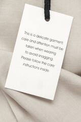 Close up of luxury clothing hang tag. Delicate garment swing tag. Laundry care washing instructions clothes label.	