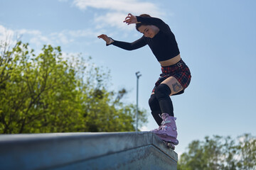 Young female grinding on a ledge in a skatepark. Aggressive inline skater athlete performing a...