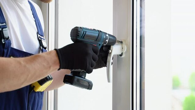 Worker in overalls installing a window lock for home safety. Window Lock How-To. Children s Injury