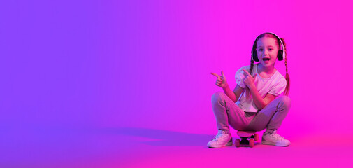 Happy girl having fun on luminous background, using wireless headphones