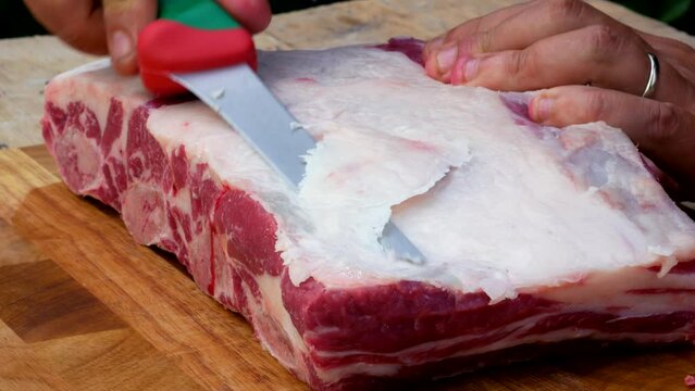 Griller cleans and checks rib rack of beef