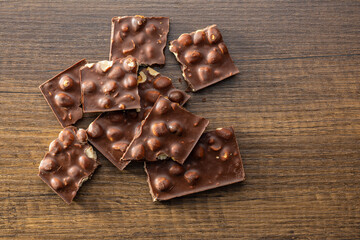 Broken chocolate bars with  nuts on wooden table. Top view.