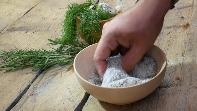 Hand in a wooden bowl mixes salt and pepper
