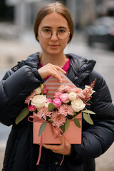 Very nice young woman holding bouquet of roses and chrysanthemums flowers