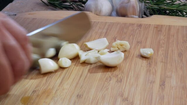 Chopping garlic with knife on cutting board