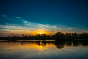 Fototapeta premium The sun sets over the lake.