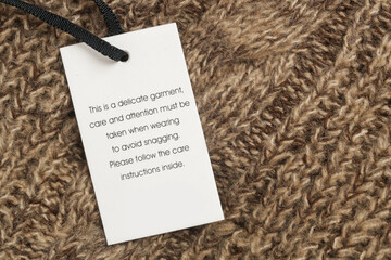 Close up of luxury clothing hang tag. Delicate garment swing tag. Laundry care washing instructions...