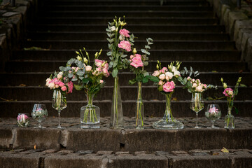 Pink and white flovers with crystal vases stands on stone stairs