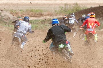 Unrecognized athletes riding a sports motorbike racing fast on a motocross track field. Challenge...