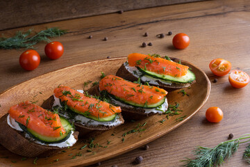 Red fish sandwich with cucumber food photo on a wooden table
