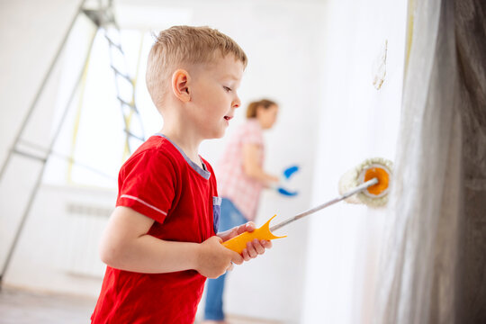 Mother and child son paint the wall with paint using roller and brush