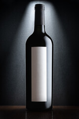 Isolated black wine bottle with a white glare and a white blank label for text on a white background