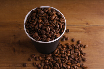 a paper cup of coffee on a wooden table with coffee beans