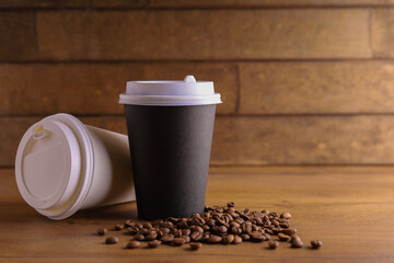 a paper cup of coffee on a wooden table with coffee beans