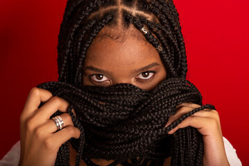 Close-up portrait of black woman with holding her braids to her face.