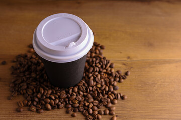 a paper cup of coffee on a wooden table with coffee beans