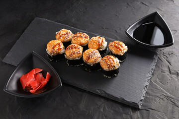 Sushi and rolls set on a black plate and black background