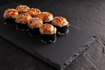 Sushi and rolls set on a black plate and black background