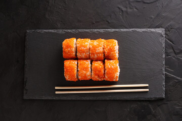 Sushi and rolls set on a black plate and black background