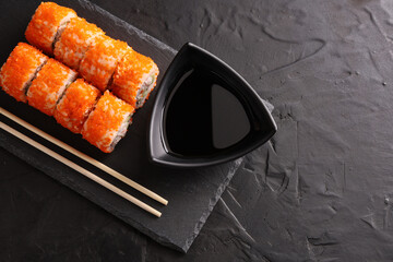 Sushi and rolls set on a black plate and black background