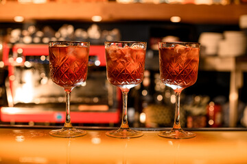 Red cocktails with ice cubes in old styled glasses on the bar counter in the bar