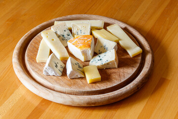Cheese platter with different kinds of cheese on wooden table