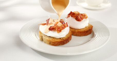 poached egg toast topped with hollandaise sauce. benedict egg. serving breakfast on a white background. sunny day. angle view.