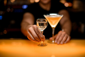 Barman serving glass with transparent bubble liquid. fresh yellow martini cocktail stands nearby