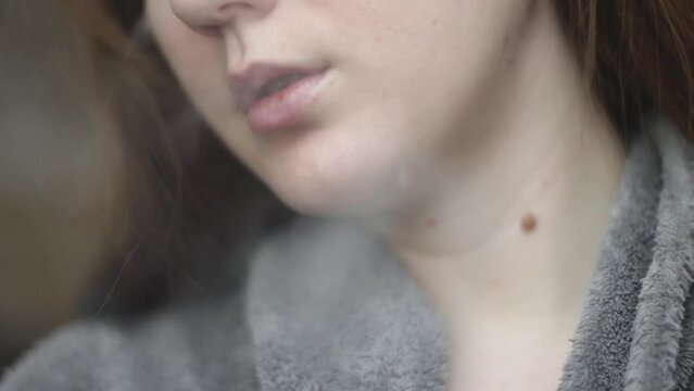Young girl blows smoke from her mouth using an electronic cigarette. Mouth close up view