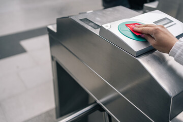 Unrecognizable woman's hand swiping a public transport card through the magnetic sensor at the station access turnstile.