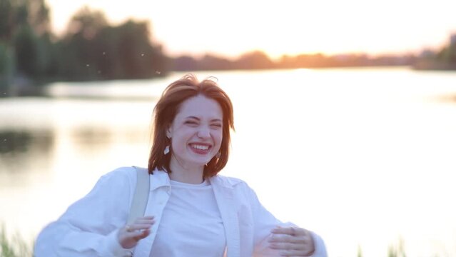 young happy woman rejoices at sunset by the lake, concept of harmony and joy.
