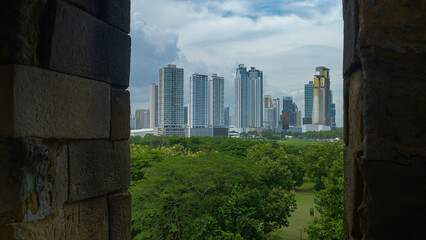 Window view from Panama Viejo of lush trees and modern district of Panama City