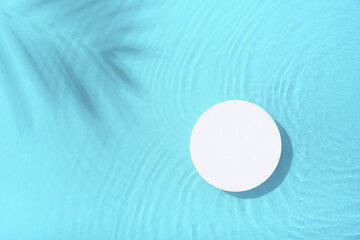 Podium or pedestal with blue water ripple and palm shadow flat lay, top view. Summer cosmetic template, mock up
