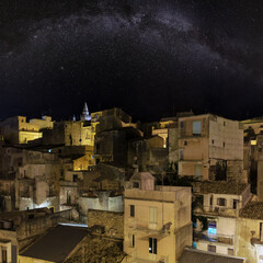 Night old medieval Ragusa town view (Sicily, Italy) with Milky Way Galaxy stars in sky. City lights of famous touristic destination. Unesco world heritage site.