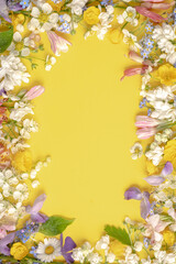 floral layout from different wildflowers on a light yellow background. Template for advertising and presentation of cosmetic products. Top view and copy space. Vertical photo