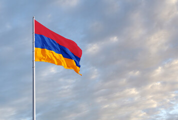 Waving Armenian flag against a blue sky with clouds and empty space for text. Room for text.