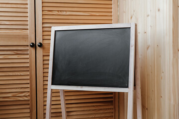 Fototapeta na wymiar The blank black drawing board with wooden frame in interior. Blank slate