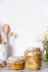 Fototapeta na wymiar Jars with honey and walnuts. Walnuts in honey in the kitchen interior