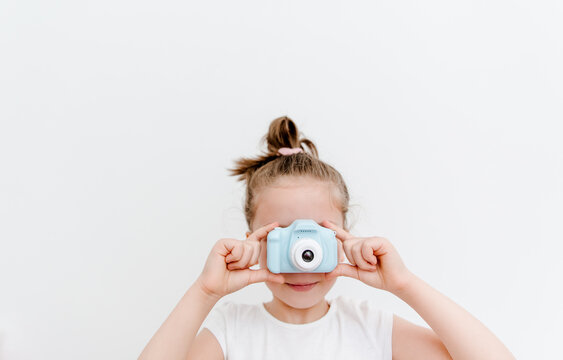 The gadgets for kids. Cute small todler girl with toy photo camera. White background.