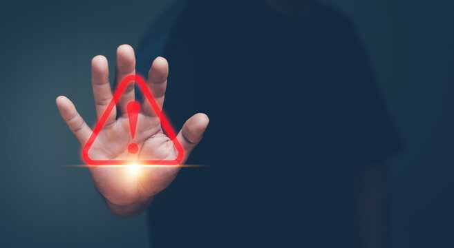 Human hand showing red triangle caution warning sign for maintenance notification error and risk concept.