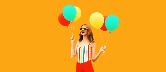 Summer portrait of happy smiling young woman with bunch of colorful red yellow balloons having fun...