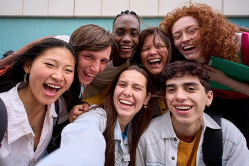 Cell phone selfie of excited multiracial group of erasmus college students together outside....
